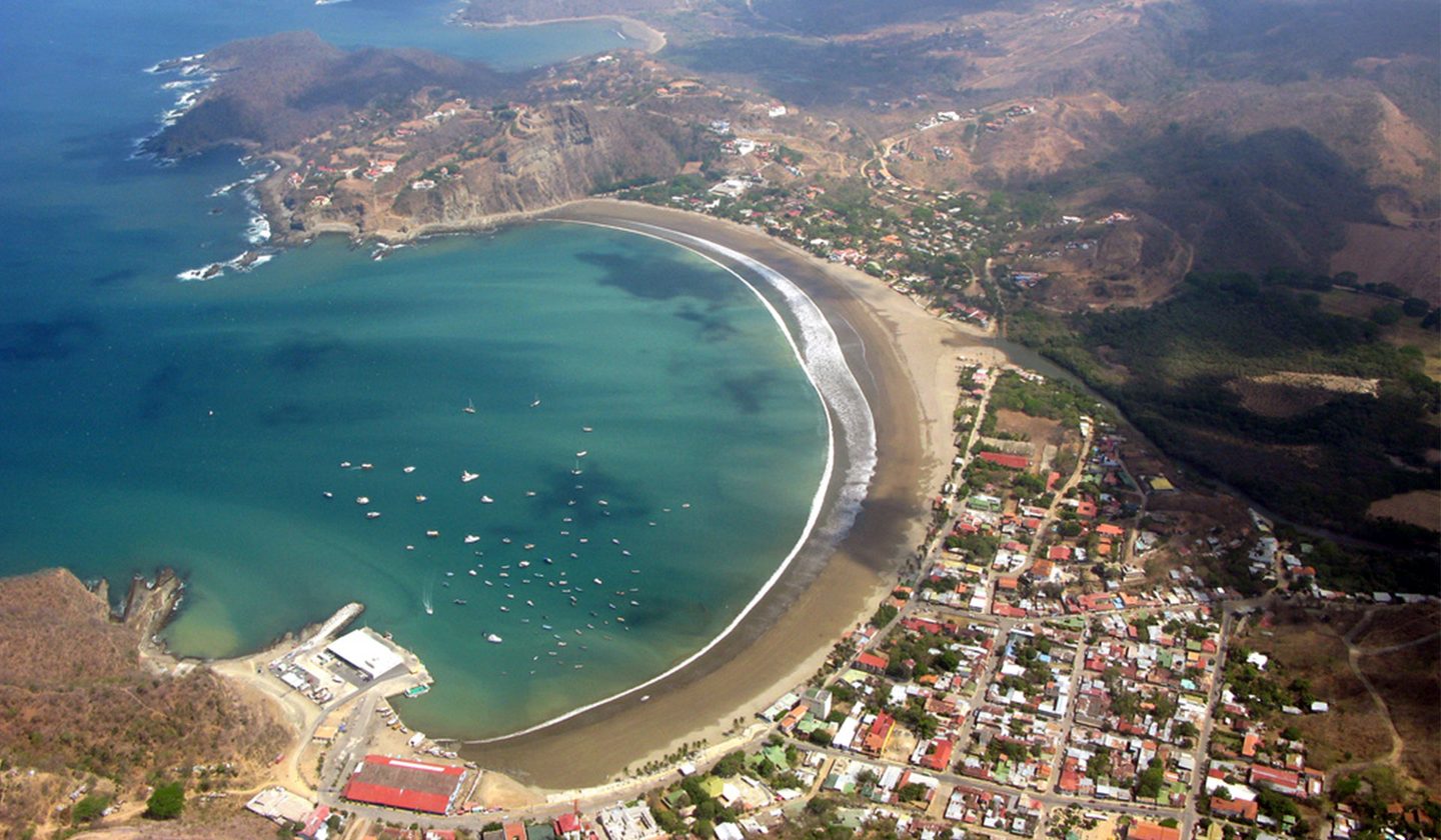 Aerial view of San Juan del Sur bay, Nicaragua — the horseshoe beach, the town and boats at anchor