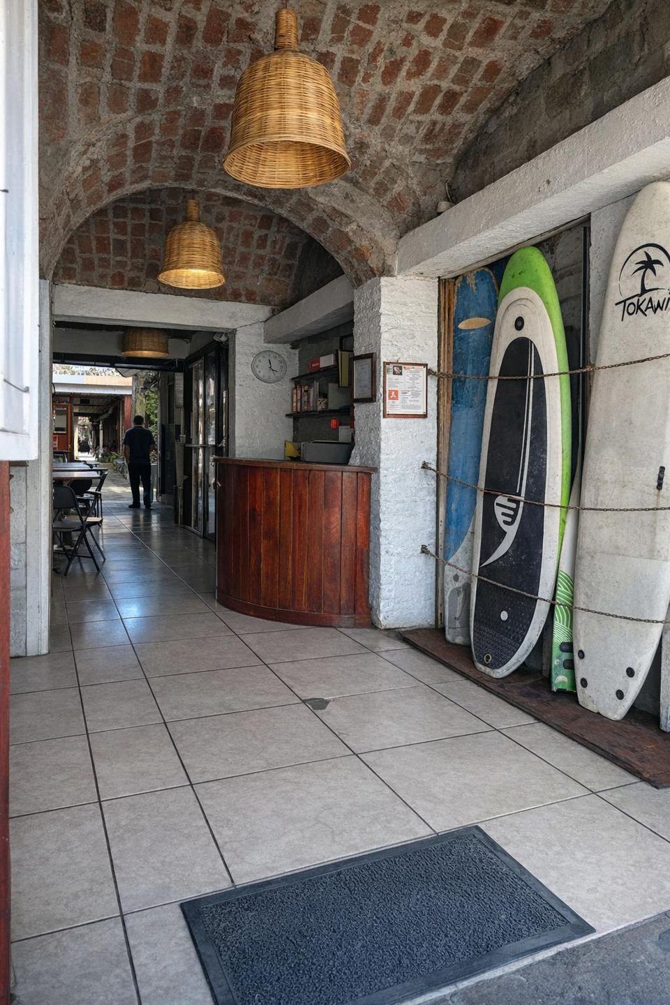 Reception and hallway at Hostal Los Chamos with surfboards leaning against the wall