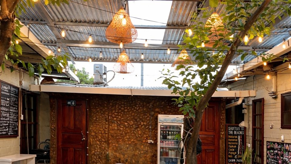 The courtyard at Hostal Los Chamos — tables and chairs under string lights and a tree, San Juan del Sur